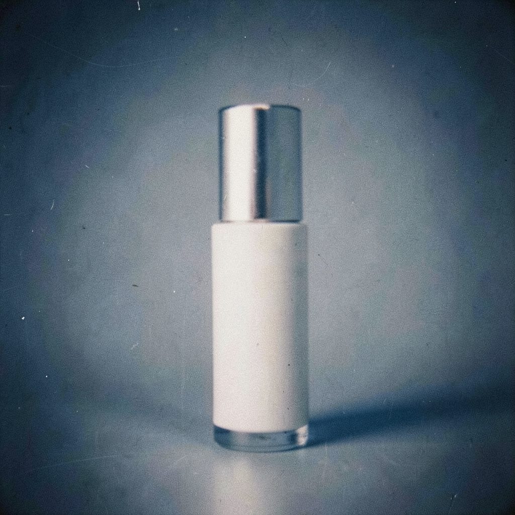 Moody editorial still life of cosmetic serum bottles and a folded towel on a deep navy background, warm amber accents, soft analog film grain