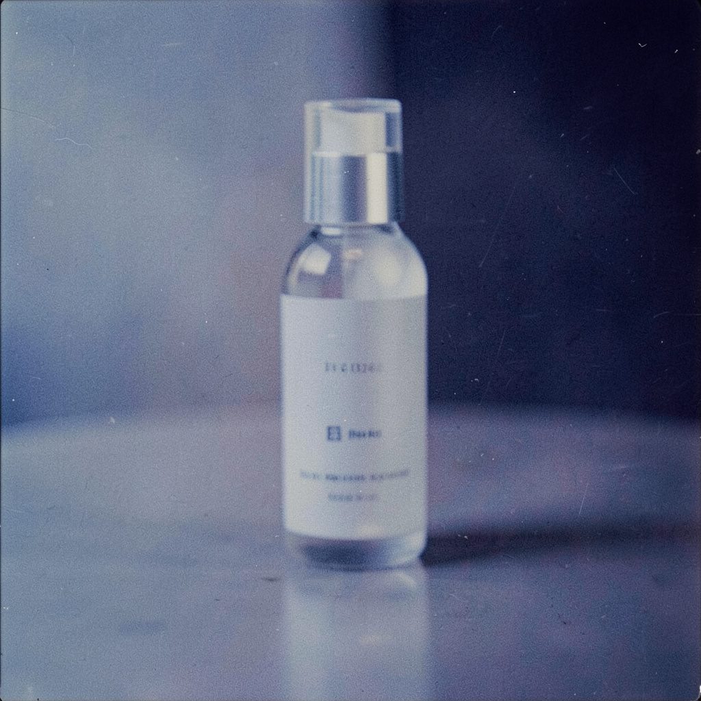 An analog film photograph of a single cosmetic product on a pale neutral surface, soft daylight, visible grain, calm minimalist mood